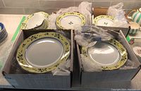 Boxes containing various piles of plates and bowls with yellow olive branch pattern