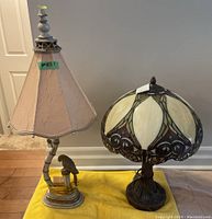 Photo of two lamps: parrot themed lamp with fabric shade and faux Tiffany style lamp with stained glass shade.