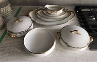 Full set of Theodore Haviland Limoges seven serving ware pieces on countertop including plates, casseroles, bowl, and gravy boat