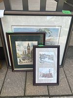 Three framed prints placed against a wall, showing full frames including visible labels with dimensions.