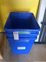 Three blue recycling bins stacked and positioned on the floor, showing size label and front details.