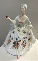 Front view of the Royal Doulton Diana porcelain figurine showing colorful floral skirt, pink bow, and red flower in hand.