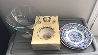 Overview of Bunnykins bowl and cup set in original box, blue and white Wedgwood plate, and clear footed glass bowl.