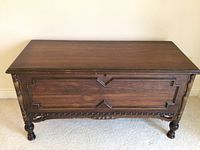 Full front view of the vintage cedar hope chest showing carved accents and turned legs.