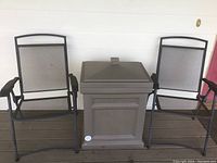 Two black metal folding chairs and one plastic delivery box arranged on porch