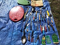 Photo showing all gardening tools, gloves, and kneeling pads spread on blue tarp outdoors
