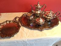 Full coffee service set on large ornate tray with separate round platter to the side, showing overall collection and design coherence.