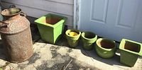 All ceramic planter pots and vintage metal pot arranged on the ground near a white door