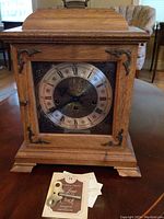 Front view of wooden mantel clock with brass spandrels and handle
