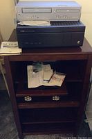 Media cabinet with shelves and detached glass door, wood finish, holding electronics