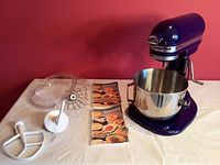 Mixer with bowl, accessories and manuals laid out on table