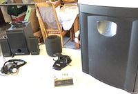 Shows full view of Altec Lansing speaker set, black office shredder, wired headphones, paper punch, and new digital voice recorder on a table