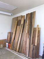 Full view of tall wood pieces stacked against a wall including plywood and trim boards