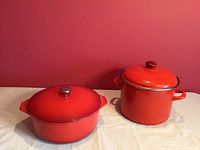Front side view of both pots, showing bright red color and lids on each.