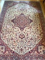 Full view of the larger rug showing the central medallion and overall condition including wear and edging