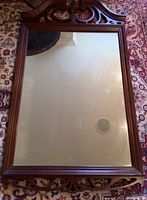 Full view of the vintage wood wall mirror showing the rectangular reflective glass with carved wooden frame and top decorative crest.