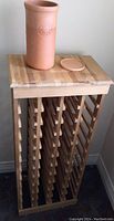 Front angled view of wood wine rack with ceramic wine bucket on top