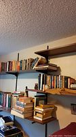 Wide view of multiple shelves with assorted books, some stacked and others upright.
