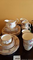 Full set of Royal Albert PetitPoint china includes stacked plates, cups, milk jug, and more arranged on a table.