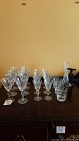 Group shot of all crystal glasses, vase, stopper, opener on wooden surface