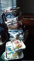 Stack of assorted kitchen linens including placemats, tea towels, oven mitts, and food wraps.