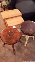 Photo showing two wooden stools with claw feet and two wooden nesting tables with turned legs on carpeted floor.