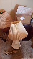 Full lot showing milk glass hobnail lamp with wired plug, additional lampshade, and sofa armrest table top tray with original box behind