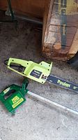 Poulan 16 inch chainsaw with green Weed Eater string trimmer on concrete floor.
