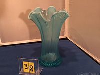 Blue opalescent ribbed glass vase with ruffled top edge, shown against a plain background with item number 38 in front