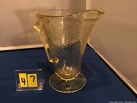 Yellow Depression glass pitcher with etched Florentine No.2 design, about 7.5 inches tall, shown from front with visible handle and pouring spout.