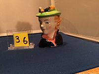 Front view of ceramic head vase showing young lady in green hat with decoration.