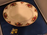 Oval platter showing floral pattern around scalloped edge with gold trim, no chips or cracks visible, slight wear marks in center.