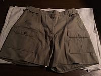 Front view of ladies khaki Tilley shorts size 14 laid flat showing front flap pockets and belt loops.