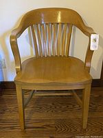 Front view of the oak wood chair showing curved armrests and vertical slatted backrest with seat scrapes