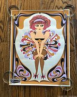 Colorful stylized print showing a cartoon woman with retro design by Elaine Havelock held down with glass weights on corners