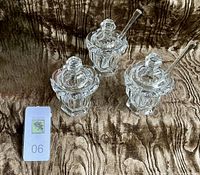 Three Baccarat Bretagne crystal mustard jars on fabric background with one spoon missing