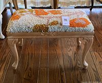 Front view of a blonde wood bench with cabriole legs and a latch-hook rug covering the seat showing overall condition and design.