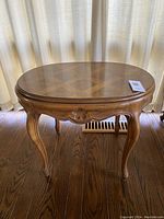 Full view of oval side table showing French Provincial curved legs and carved apron.