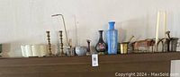 Wide view of all decorative objects arranged on wooden shelf, showing vases, candlesticks, boxes, and other items.