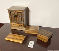 Full view of the lot showing one wooden jewelry cabinet and four assorted wooden boxes with inlaid designs.
