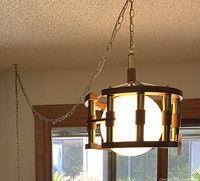Front and side views of the mid-century modern hanging light fixture in a living room setting with bookshelves in the background.