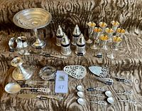 Group view showing all silver items including candlestick, compote, cordial glasses, spoon collection, servers, salt and pepper shakers, napkin rings, shoehorn, butter spreader and ashtray.