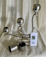 Sterling silver three candle holder with two pewter napkin rings in front.