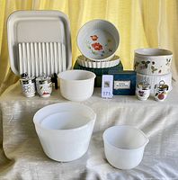 Full display of prep and serving pieces including mixing bowls, Corning Ware roasting rack and browning tray, egg coddlers in box, and ceramic jars