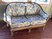 Front view of bamboo frame loveseat showing floral fabric cushions and lattice side design.