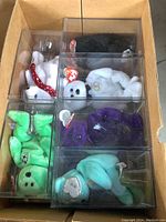 Top-down photo showing several TY Beanie Babies in clear display boxes in a brown cardboard box.