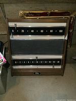 Full view of the vintage wooden framed billiards scoreboard with two sliding metal markers and measuring approximately 25 by 26 inches.