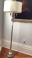 Full view of the vintage floor lamp showing the metal base, slim pole, and paper shade with multiple bulb sockets beneath the shade.