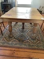 Front angle showing robust carved legs and the table top with visible wear and paint splatter