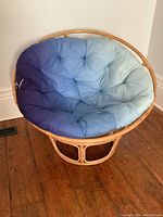 Full view of the bamboo papasan chair with blue gradient seat cushion placed on wooden floor.